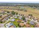 Wide aerial view showcasing neighborhood homes, lush green lawns, and a golf course with a tranquil pond at 17645 Se 117Th Cir, Summerfield, FL 34491