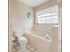Well-lit bathroom showcasing tub with white tile surround and adjacent toilet and window at 17645 Se 117Th Cir, Summerfield, FL 34491