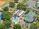 Aerial view featuring a pool, tennis court, shuffleboard, and community buildings surrounded by trees at 17645 Se 117Th Cir, Summerfield, FL 34491
