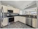 Well-equipped kitchen with stainless steel appliances, granite countertops, white cabinets, and views to living room at 17645 Se 117Th Cir, Summerfield, FL 34491