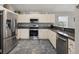 Bright kitchen featuring stainless steel appliances, white cabinets, and dark granite countertops with tile floors at 17645 Se 117Th Cir, Summerfield, FL 34491