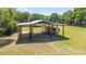 Spacious horse barn with a covered area for horse trailer parking on a well-maintained green lawn at 2720 Se 145Th St, Summerfield, FL 34491