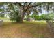 Home exterior featuring mature trees and a well-maintained lawn and fenced perimeter at 2720 Se 145Th St, Summerfield, FL 34491