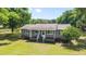 Charming single-story home with a covered front porch, green shutters, and a spacious green lawn at 2720 Se 145Th St, Summerfield, FL 34491