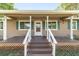 Close-up of a charming front porch with white railings, green shutters, and a welcoming entrance at 2720 Se 145Th St, Summerfield, FL 34491