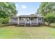 Inviting single-story home featuring a charming front porch, a well-manicured lawn, and lush green landscaping at 2720 Se 145Th St, Summerfield, FL 34491