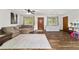 Comfortable living room with a large sectional sofa and wood-look floors with view of front door at 2720 Se 145Th St, Summerfield, FL 34491