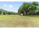 A large grassy pasture featuring mature trees, a storage shed, and ample space at 2720 Se 145Th St, Summerfield, FL 34491