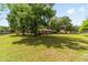 Expansive grassy yard featuring a charming single-story home in a serene setting with large shady trees at 2720 Se 145Th St, Summerfield, FL 34491