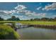 Scenic golf course view featuring a water hazard with a wooden bridge under a partly cloudy sky at 4945 Nw 35Th Lane Rd, Ocala, FL 34482