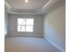 A bedroom showcasing a decorative tray ceiling and a view to the backyard at 6104 Sw 147Th Street Rd, Ocala, FL 34473