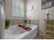 Soaking tub with a wooden tray, shuttered window, and decorative tile surround at 6437 Sw 45Th Ave, Ocala, FL 34474