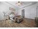 A spacious bedroom with a tray ceiling, wood-look floors, ceiling fan, and a lovely bed at 6437 Sw 45Th Ave, Ocala, FL 34474