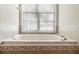 Close-up of a soaking tub featuring tiled walls and a large window offering natural light and scenic views at 802 Se 50Th Ter, Ocala, FL 34471