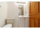 View of bathroom with white walls, wood door, vanity and toilet at 828 Ne 51St Ave, Ocala, FL 34470