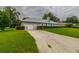 Spacious backyard with a long driveway leading to a detached garage, surrounded by green grass and shrubs at 828 Ne 51St Ave, Ocala, FL 34470