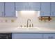 Close-up of kitchen featuring blue cabinets, and a white double sink at 828 Ne 51St Ave, Ocala, FL 34470