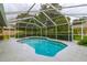 Inviting screened-in pool with a blue-tiled edge, surrounded by a spacious patio and green foliage at 828 Ne 51St Ave, Ocala, FL 34470