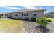 Rear of the home with grey paint, manicured bushes, landscaping, and green lawn at 8820 Sw 104Th Cir, Ocala, FL 34481