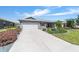 Well-maintained home with a long driveway, lush landscaping, and an attached garage at 8820 Sw 104Th Cir, Ocala, FL 34481
