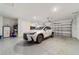 Two car garage features an epoxy floor, white walls, a new white SUV, and ample overhead lighting at 8820 Sw 104Th Cir, Ocala, FL 34481
