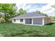 The backyard shows a covered patio with a door to the home, green lawn, and lush trees at 8878 Sw 133Rd Lane Rd, Ocala, FL 34473