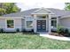 Lovely gray home that includes manicured lawn, garden bed, and a modern front door at 8878 Sw 133Rd Lane Rd, Ocala, FL 34473