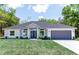 Beautiful home featuring a manicured lawn, gray paint, and a matching garage door at 8878 Sw 133Rd Lane Rd, Ocala, FL 34473
