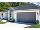 Exterior angle of home showing the 2 car garage door, landscaping and neutral paint at 8878 Sw 133Rd Lane Rd, Ocala, FL 34473