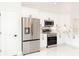 White kitchen showcasing stainless steel refrigerator, range, microwave, white cabinets, and marble countertops at 8878 Sw 133Rd Lane Rd, Ocala, FL 34473