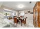 Open-concept dining area with wicker chairs, a wooden table, and a view into the living room featuring natural light at 9015 Sw 94Th St # D, Ocala, FL 34481