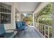 Relaxing covered front porch with comfortable blue seating, offering views of mature trees at 9015 Sw 94Th St # D, Ocala, FL 34481