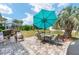 Inviting back patio with stone pavers, umbrella-covered dining set, and beautiful backyard views; perfect for al fresco dining at 9290 Se 120Th Loop, Summerfield, FL 34491