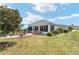 Well-maintained backyard featuring lush lawn, landscaped garden beds, a charming patio, and a sunroom at 9290 Se 120Th Loop, Summerfield, FL 34491