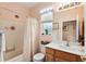 A bathroom with white shower curtain, oak cabinets, white countertop, and a large mirror creates a tranquil space at 9290 Se 120Th Loop, Summerfield, FL 34491