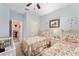 A bedroom with two beds, floral comforters, ceiling fan, and a white crib offers lots of sleeping space at 9290 Se 120Th Loop, Summerfield, FL 34491