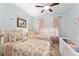 A bedroom with two beds, floral comforters, ceiling fan, and a white crib offers lots of sleeping space at 9290 Se 120Th Loop, Summerfield, FL 34491