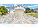 Paver driveway leading to a well-maintained home with a two-car garage, showcasing the property's curb appeal at 9290 Se 120Th Loop, Summerfield, FL 34491