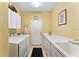 The yellow laundry room offers cabinets, countertop, washer, dryer, and a door to the garage at 9290 Se 120Th Loop, Summerfield, FL 34491