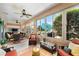 Comfortable sunroom with multiple seating areas, ceiling fans, and windows offering serene views of the landscaped backyard at 9290 Se 120Th Loop, Summerfield, FL 34491