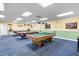 The billiard room features billiard tables, overhead lighting and blue carpet at 9579 Sw 195 Cir, Dunnellon, FL 34432