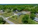 Aerial view of a home with a pool, large yard, a detached garage and surrounded by lush trees at 2563 Se 156Th Place Rd, Summerfield, FL 34491