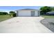 Detached garage with a large white door, driveway and small garden at 2563 Se 156Th Place Rd, Summerfield, FL 34491