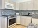 Modern kitchen featuring stainless steel appliances, light gray cabinets, and mosaic tile backsplash at 4998 Nw 30Th Pl, Ocala, FL 34482