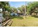 View of the backyard with a charming single-story home, screened porch, and mature trees at 10060 Se 106Th Ln, Belleview, FL 34420