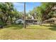View of the backyard featuring a charming home, mature trees, and spacious green lawn at 10060 Se 106Th Ln, Belleview, FL 34420