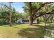 A view of the backyard with mature trees, a single-story home, and a screened porch at 10060 Se 106Th Ln, Belleview, FL 34420