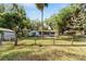 View of the backyard featuring a charming home, mature trees, and partial fencing at 10060 Se 106Th Ln, Belleview, FL 34420