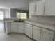 Bright kitchen showcases white cabinets, stainless steel sink and tile flooring at 16331 Se 81St Ct, Summerfield, FL 34491