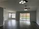 Open living room features wood-look floors, ceiling fans, and sliding glass door at 16331 Se 81St Ct, Summerfield, FL 34491